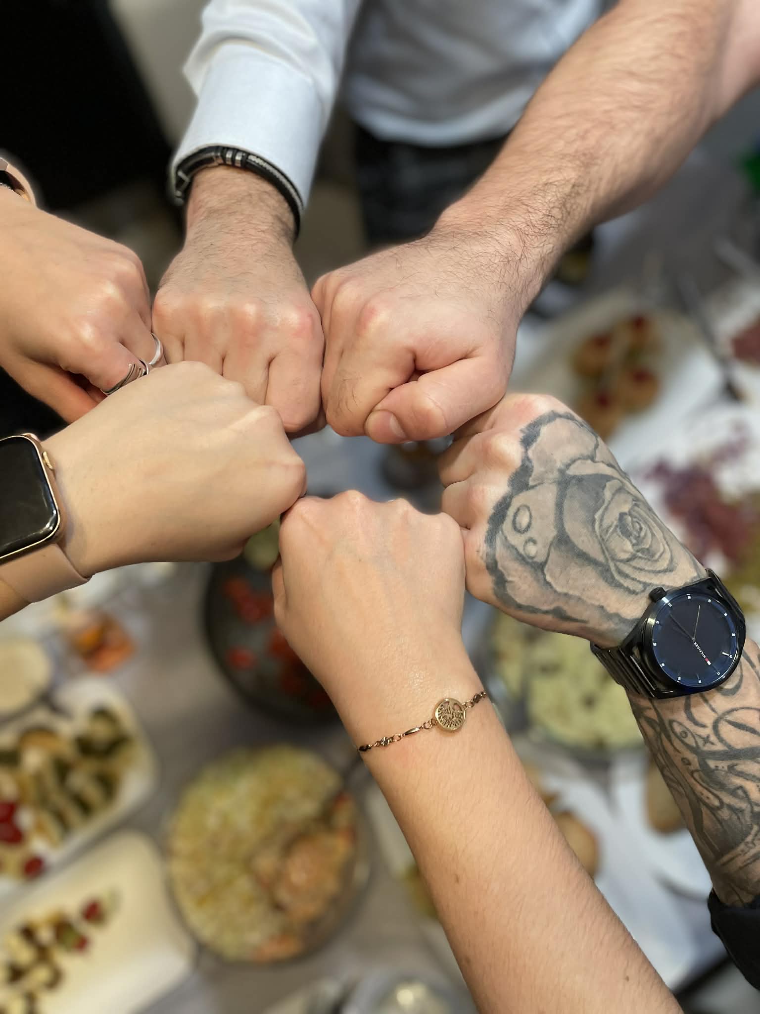 Grupa osób wspólnie spędza sylwestra, w tle widać stół pełen różnych potraw.