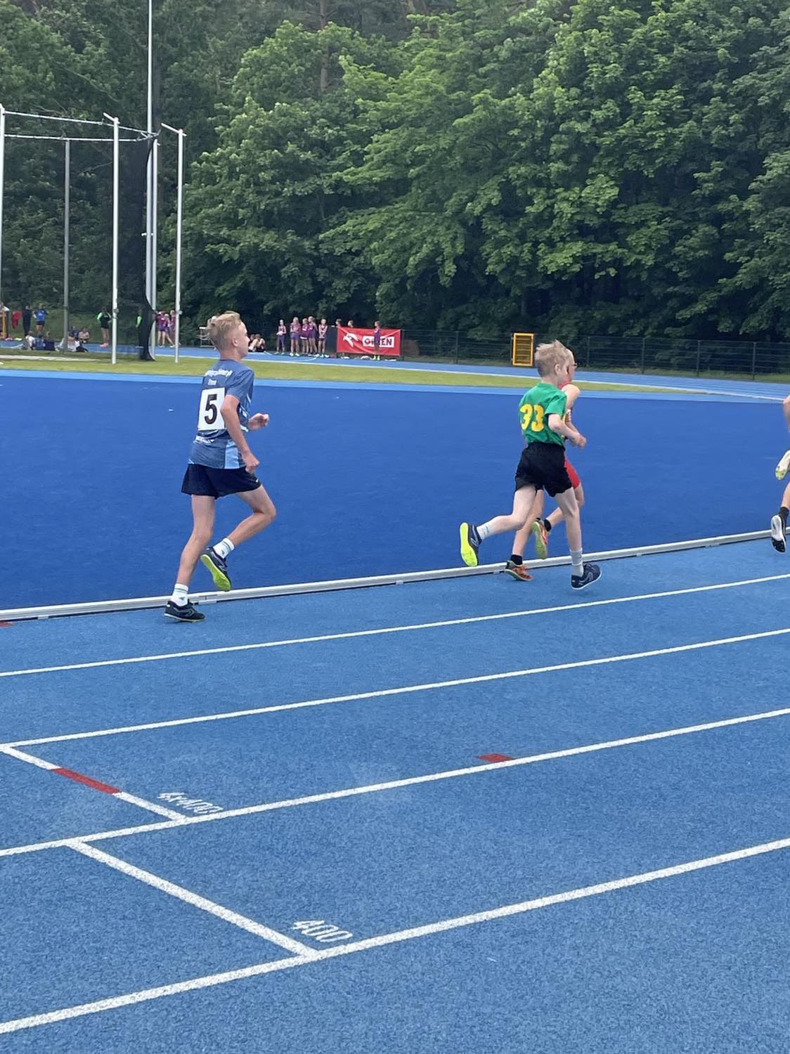Młodzi chłopcy biegną po bieżni lekkoatletycznej podczas zawodów sportowych