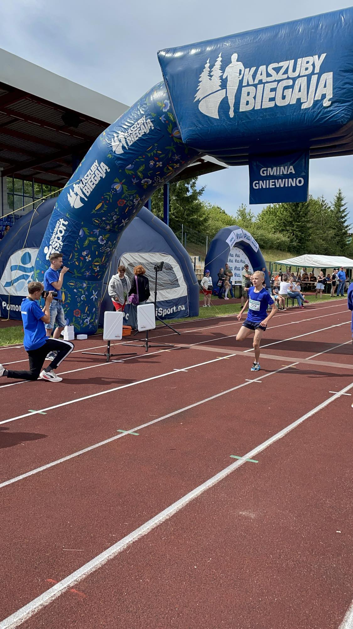 Chłopiec wbiega na metę podczas zawodów biegowych "Kaszuby Biegają" na stadionie lekkoatletycznym