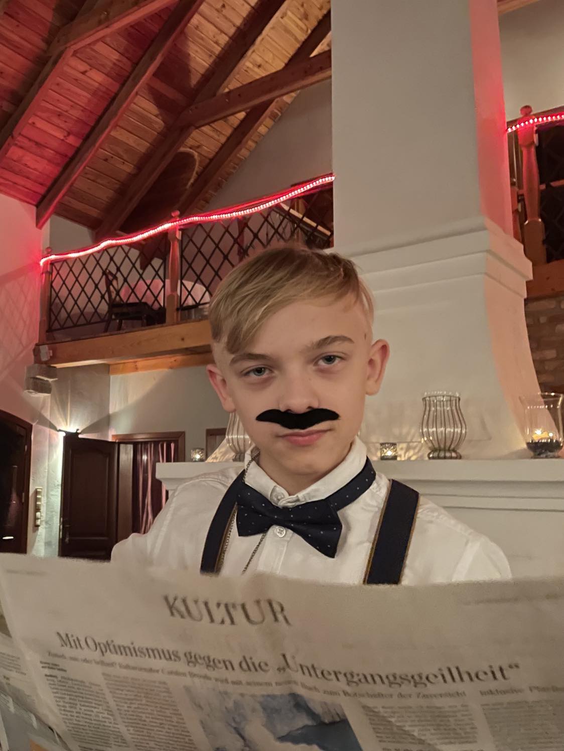 Chłopiec z doklejonymi wąsami, w koszuli z muchą