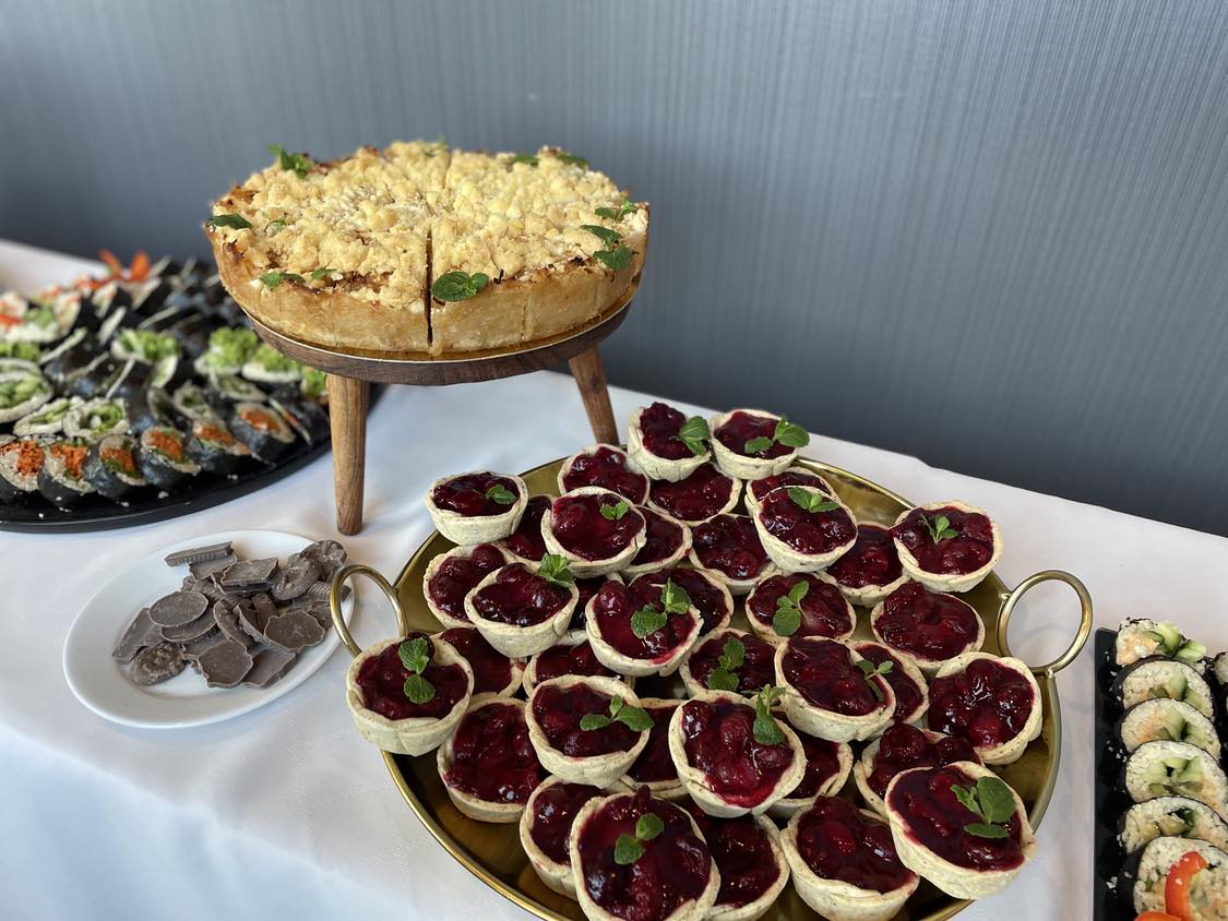 Stół bankietowy z ciastem z kruszonką, małymi tartami owocowymi i sushi